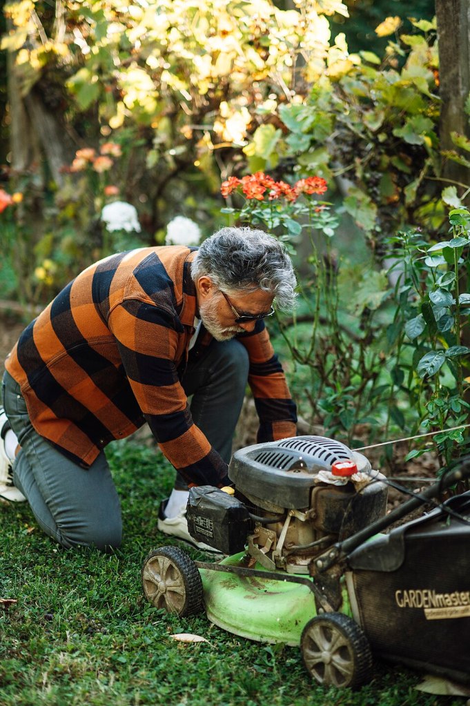 Un usuario inspecciona un cortacésped en el jardín