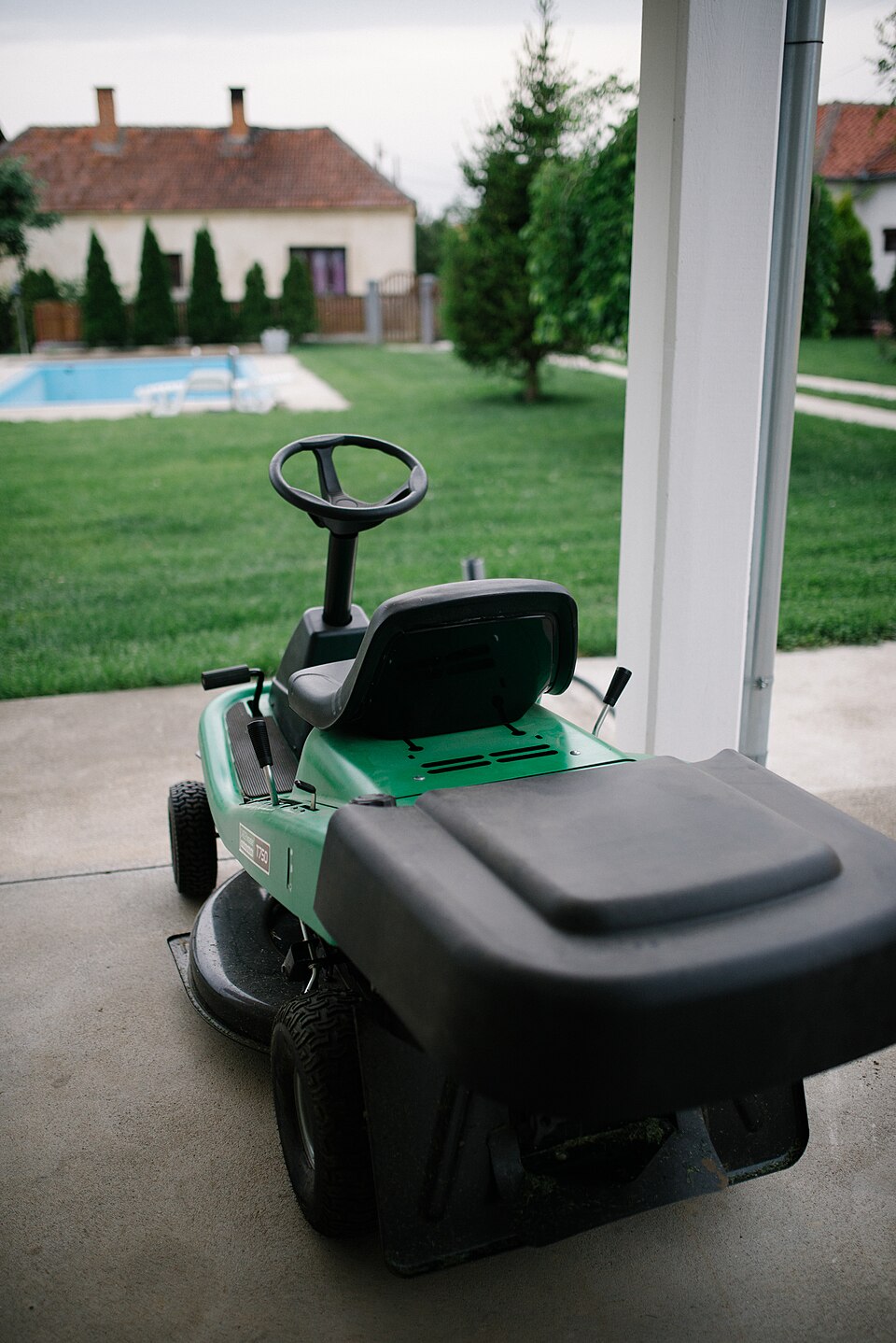 Cortacésped apagado y aparcado junto a un jardín antes de guardarlo